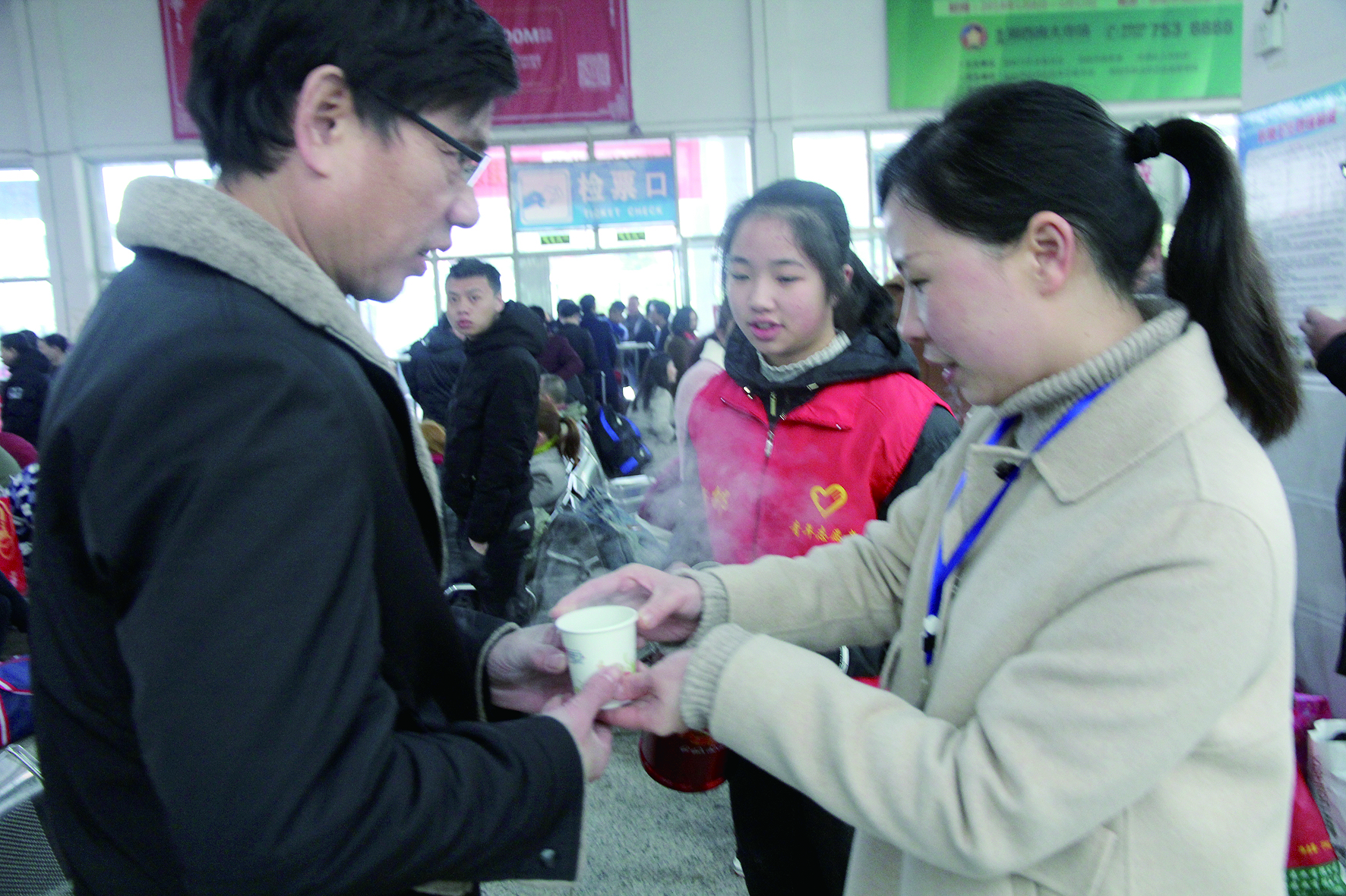 母女服務(wù)春運 2月13日，記者在新邵分公司汽車站看到，該分公司安全科副科長李喜梅與其在新邵一中初中部1701班就讀女兒劉嘉怡在車站擔(dān)當(dāng)志愿者。李喜梅在候車室耐心為旅客釋疑解惑，劉嘉怡為旅客遞上一杯杯熱茶，有時母女也相互合作，其樂融融。 祖冠 攝影報道